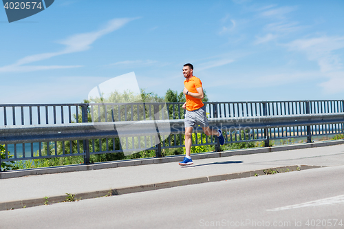 Image of smiling young man running at summer seaside