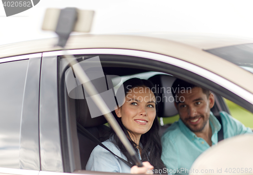 Image of happy couple in car taking selfie with smartphone