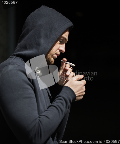 Image of close up of addict lighting up marijuana joint