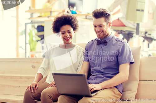 Image of happy creative team with laptop in office
