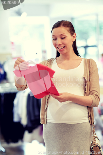 Image of happy pregnant woman shopping at clothing store