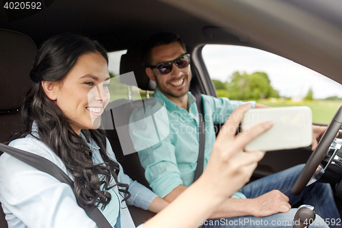 Image of happy couple in car taking selfie with smartphone