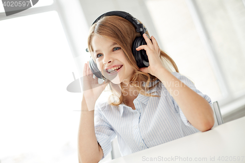 Image of smiling little girl with headphones at home