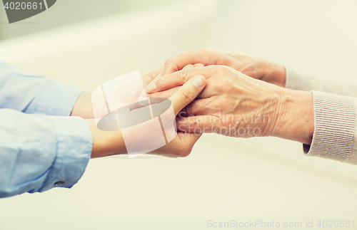 Image of close up of senior and young woman hands