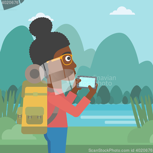 Image of Woman with backpack taking photo.