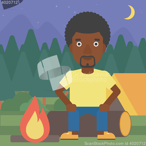 Image of Man sitting on log in the camping.
