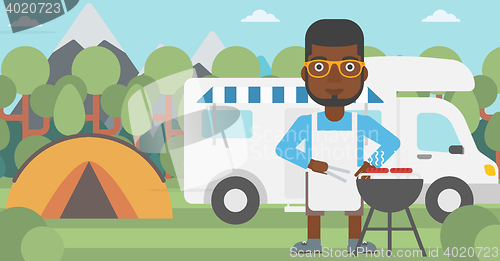 Image of Man having barbecue in front of camper van.