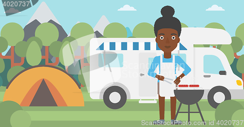 Image of Woman having barbecue in front of camper van.