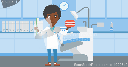Image of Dentist with dental jaw model and toothbrush.