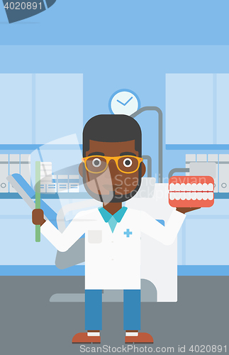 Image of Dentist with dental jaw model and toothbrush.