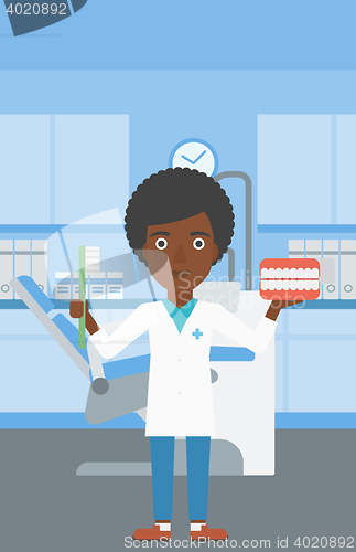 Image of Dentist with dental jaw model and toothbrush.