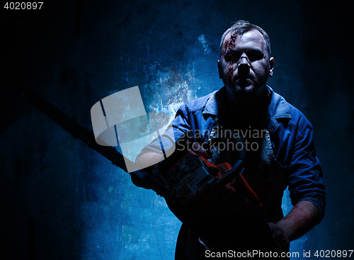 Image of Bloody Halloween theme: crazy killer as butcher with electric saw