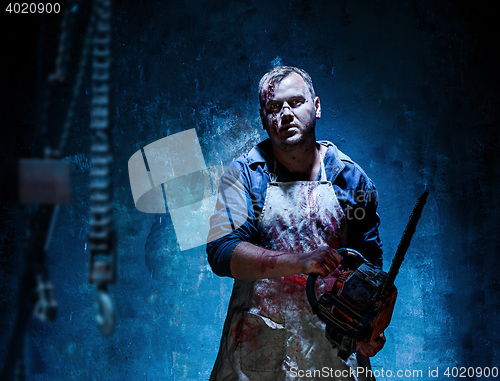 Image of Bloody Halloween theme: crazy killer as butcher with electric saw