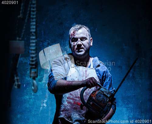 Image of Bloody Halloween theme: crazy killer as butcher with electric saw