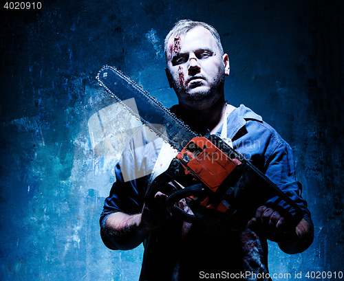 Image of Bloody Halloween theme: crazy killer as butcher with electric saw