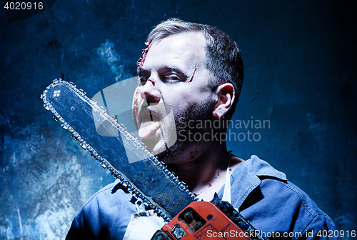 Image of Bloody Halloween theme: crazy killer as butcher with electric saw