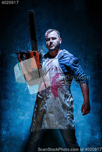 Image of Bloody Halloween theme: crazy killer as butcher with electric saw