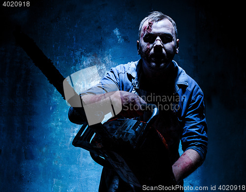 Image of Bloody Halloween theme: crazy killer as butcher with electric saw