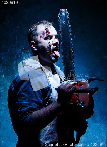 Image of Bloody Halloween theme: crazy killer as butcher with electric saw