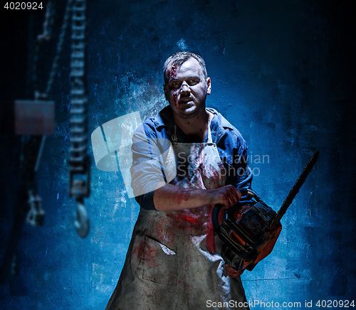 Image of Bloody Halloween theme: crazy killer as butcher with electric saw