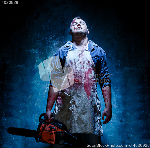 Image of Bloody Halloween theme: crazy killer as butcher with electric saw