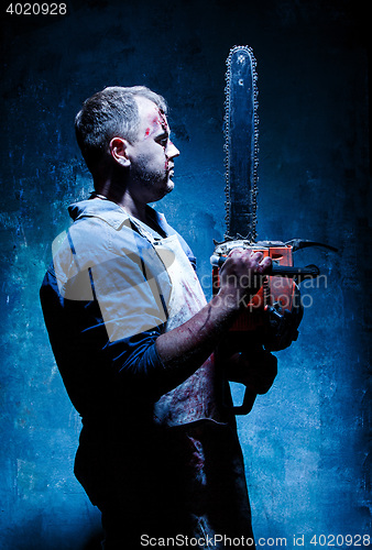 Image of Bloody Halloween theme: crazy killer as butcher with electric saw