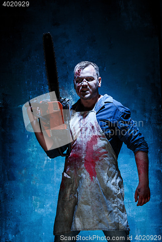 Image of Bloody Halloween theme: crazy killer as butcher with electric saw