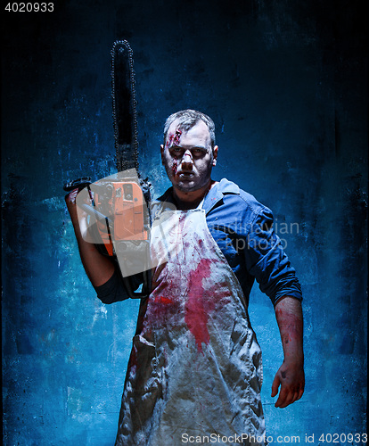 Image of Bloody Halloween theme: crazy killer as butcher with electric saw