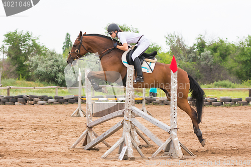 Image of Volgograd, Russia - June 19, 2016: The athlete performs a jump on a horse through the barrier on the jumping competition