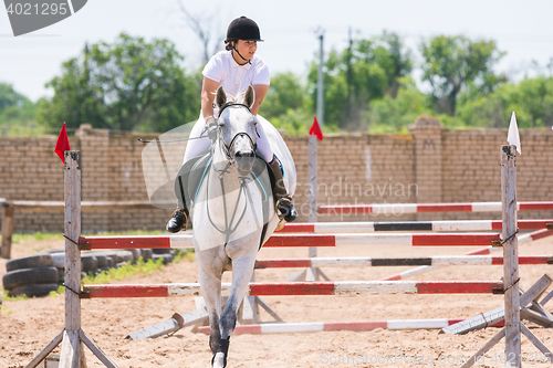 Image of Volgograd, Russia - June 19, 2016: The sportswoman on a horse has successfully completed the jump across the barrier