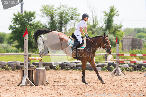 Image of Volgograd, Russia - June 19, 2016: The moment of landing a horse with rider after the jump through the barrier