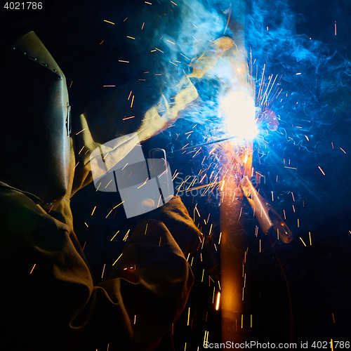 Image of welder worker welding metal by electrode