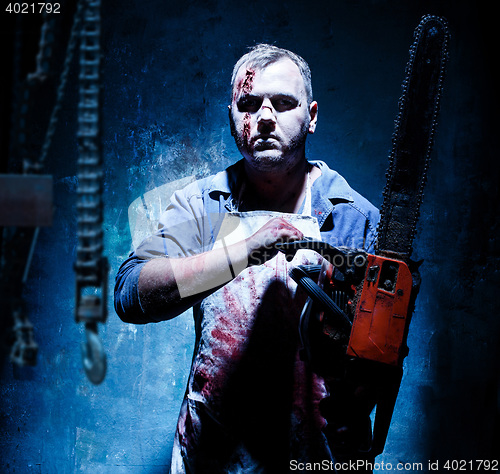 Image of Bloody Halloween theme: crazy killer as butcher with electric saw