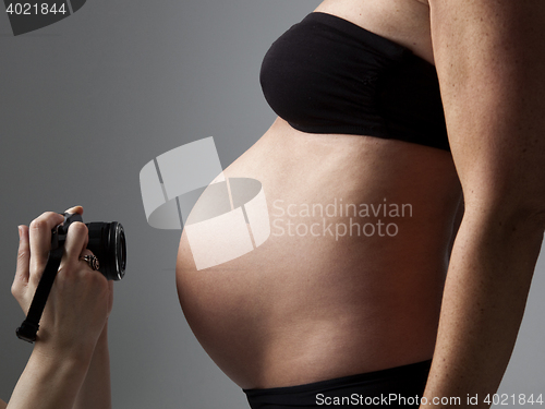 Image of belly of a pregnant woman being photographed