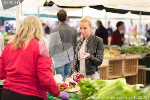 Image of Woman buying vegetable at local food market. 