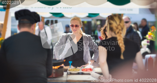 Image of Woman buying meal at street food festival.