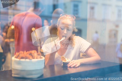 Image of Young pretty woman eating icecream in gelateria.