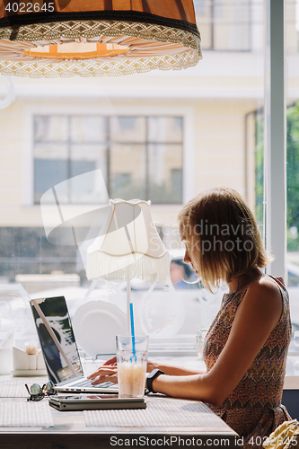 Image of Young short-haired woman using laptop in cafe