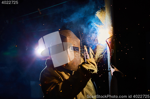 Image of welder worker welding metal by electrode