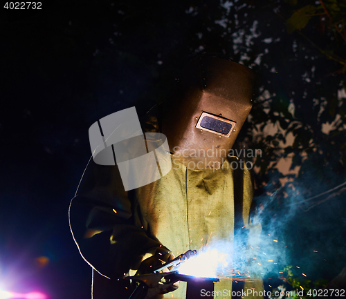 Image of welder worker welding metal by electrode