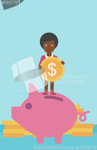 Image of Business woman putting coin in piggy bank.