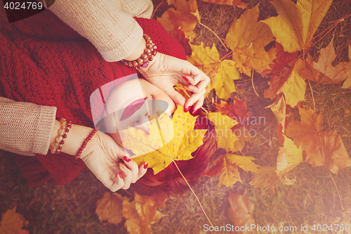 Image of Red hair girl lying with autumn maple leaf