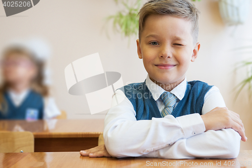 Image of Happy schoolboy sitting at desk