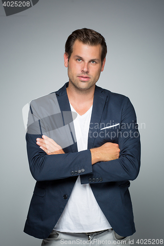 Image of Portrait of a smart young man standing with arms crossed.