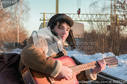 Image of Guy On Railway Tracks In Winter Playing Guitar