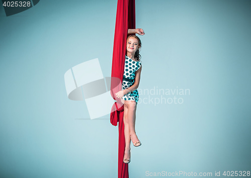 Image of Graceful gymnast sitting with red fabrics