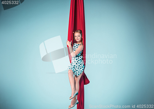 Image of Graceful gymnast sitting with red fabrics