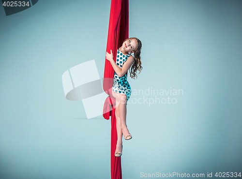 Image of Graceful gymnast sitting with red fabrics