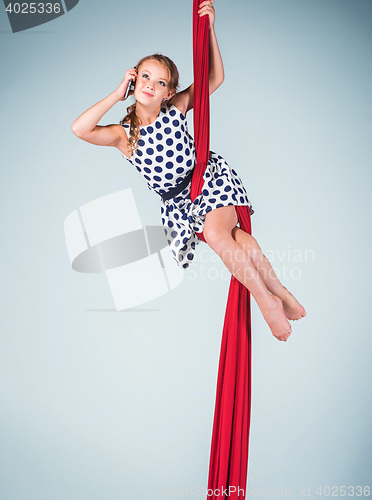 Image of Graceful gymnast sitting with red fabrics and phone