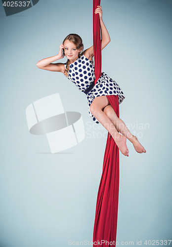 Image of Graceful gymnast sitting with red fabrics and phone